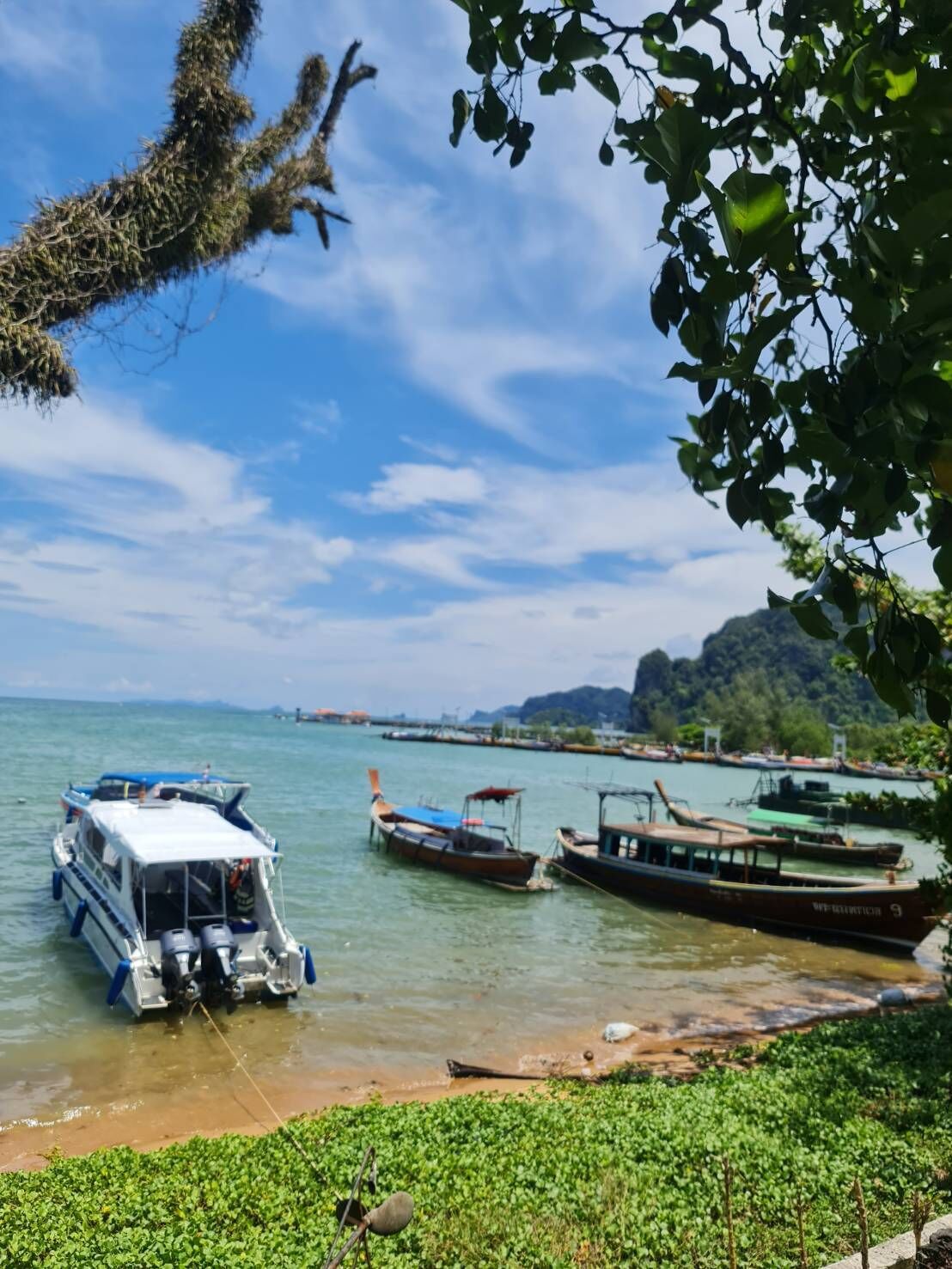 A boat docked at a calm water body with a clear sky and distant hills.