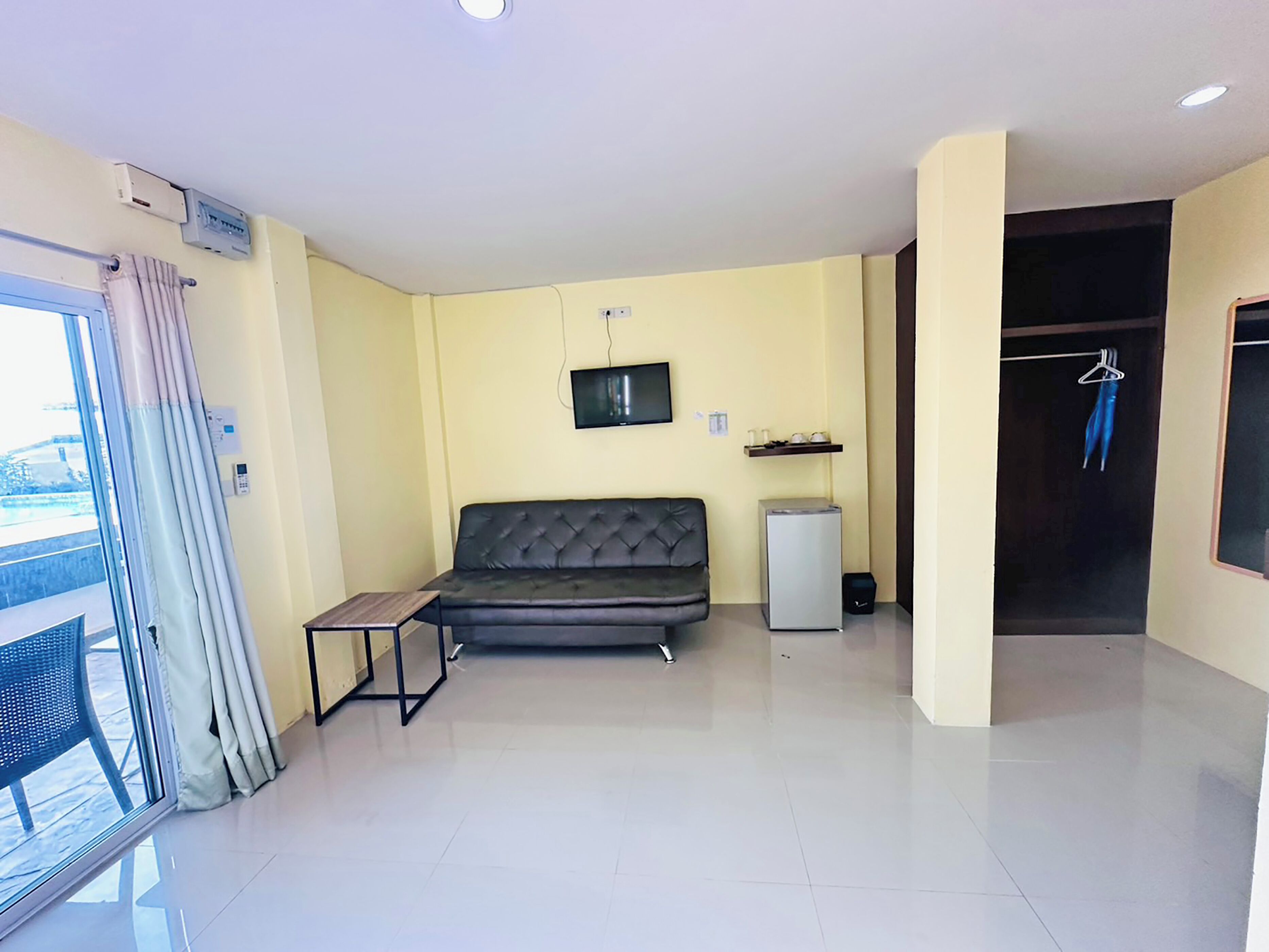 A modern living room with a sofa, a small table, a TV, and a mini-fridge.