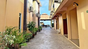 A narrow corridor with potted plants, air conditioning units, and a view of a building with a tiled roof. - Anyavee Chom By The Sea (Krabi)