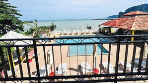 A pool area with lounge chairs and umbrellas, overlooking a calm sea and a mountainous landscape. - Anyavee Chom By The Sea (Krabi)