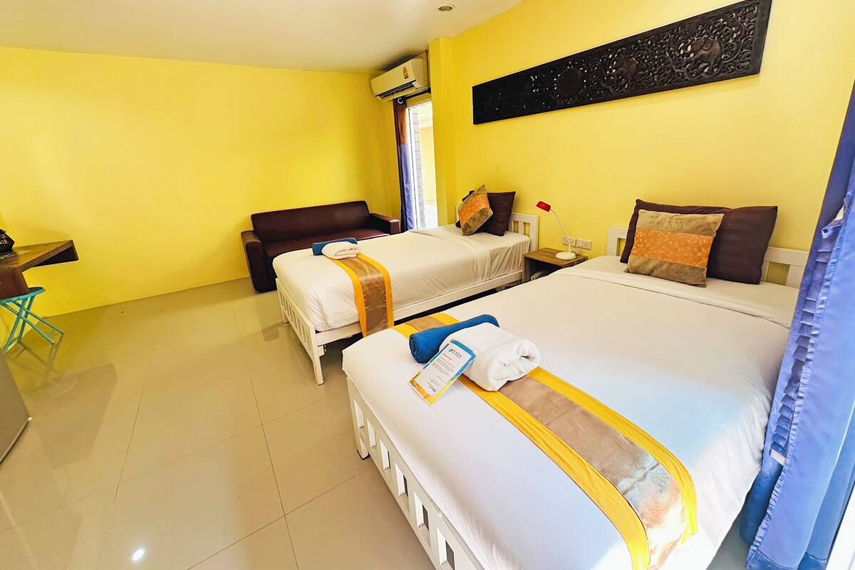Habitación de hotel con dos camas, un escritorio, una silla y un ventanal grande.