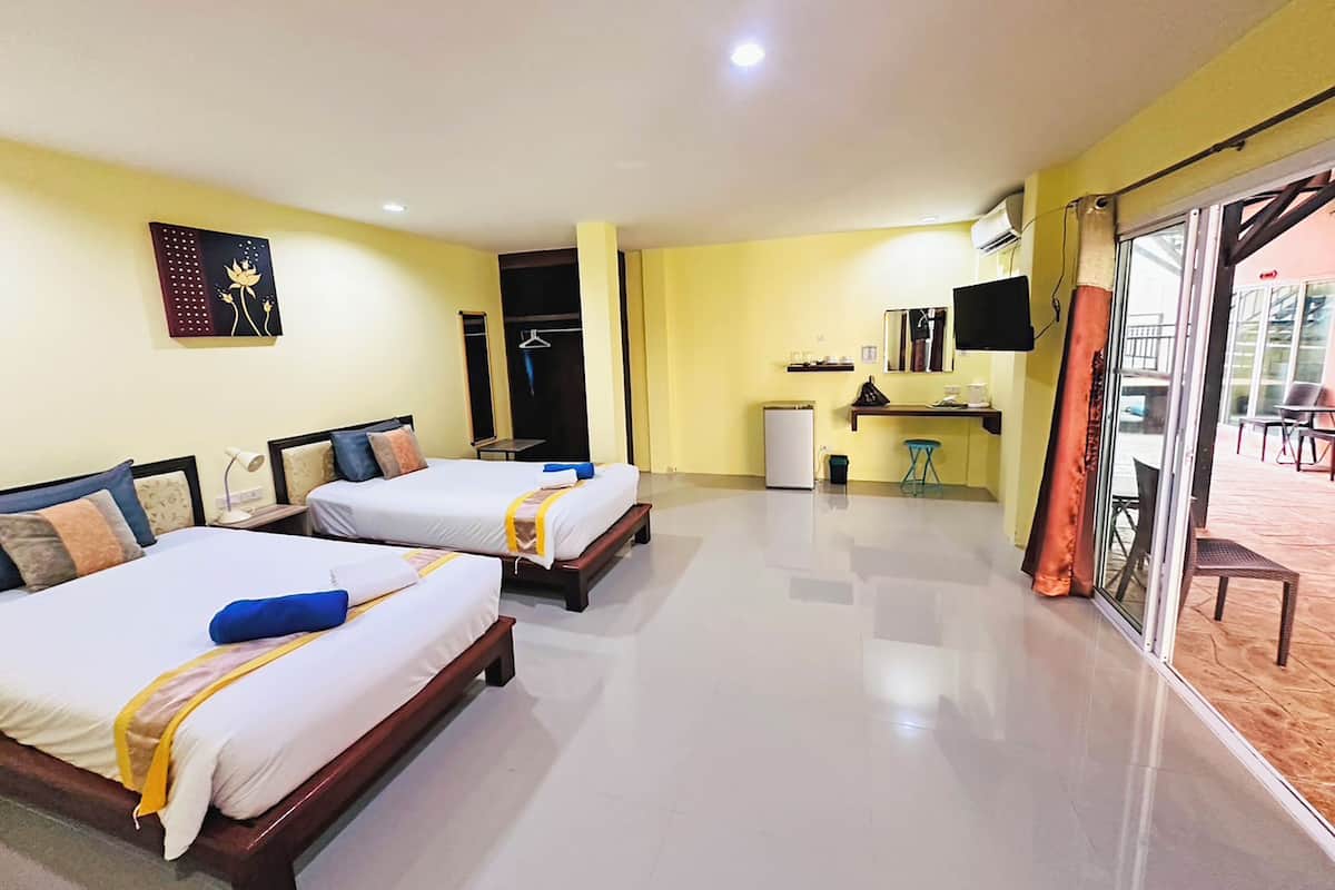 Habitación de hotel con dos camas, una kitchenette pequeña, un televisor y una puerta corrediza de vidrio a un espacio exterior.