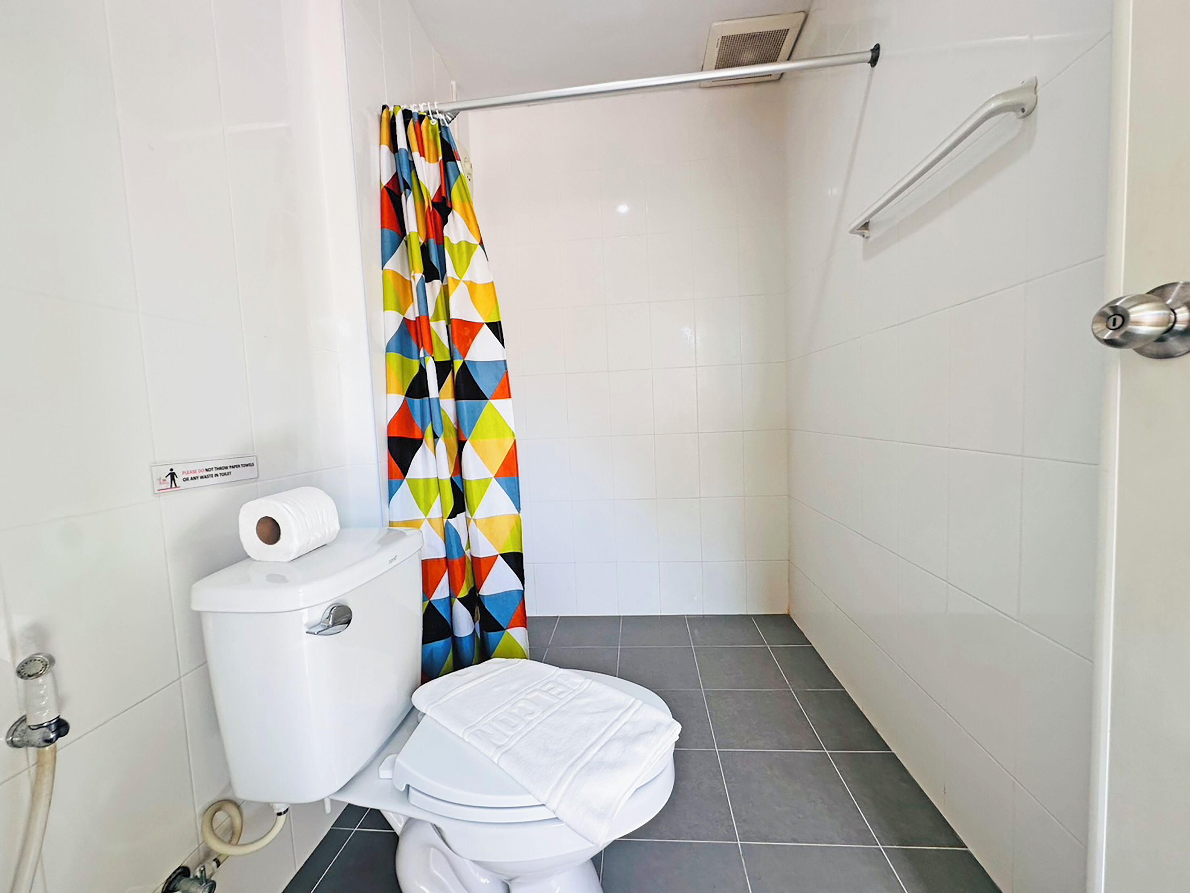 Un baño pequeño con inodoro, cortina de ducha y barra de apoyo.