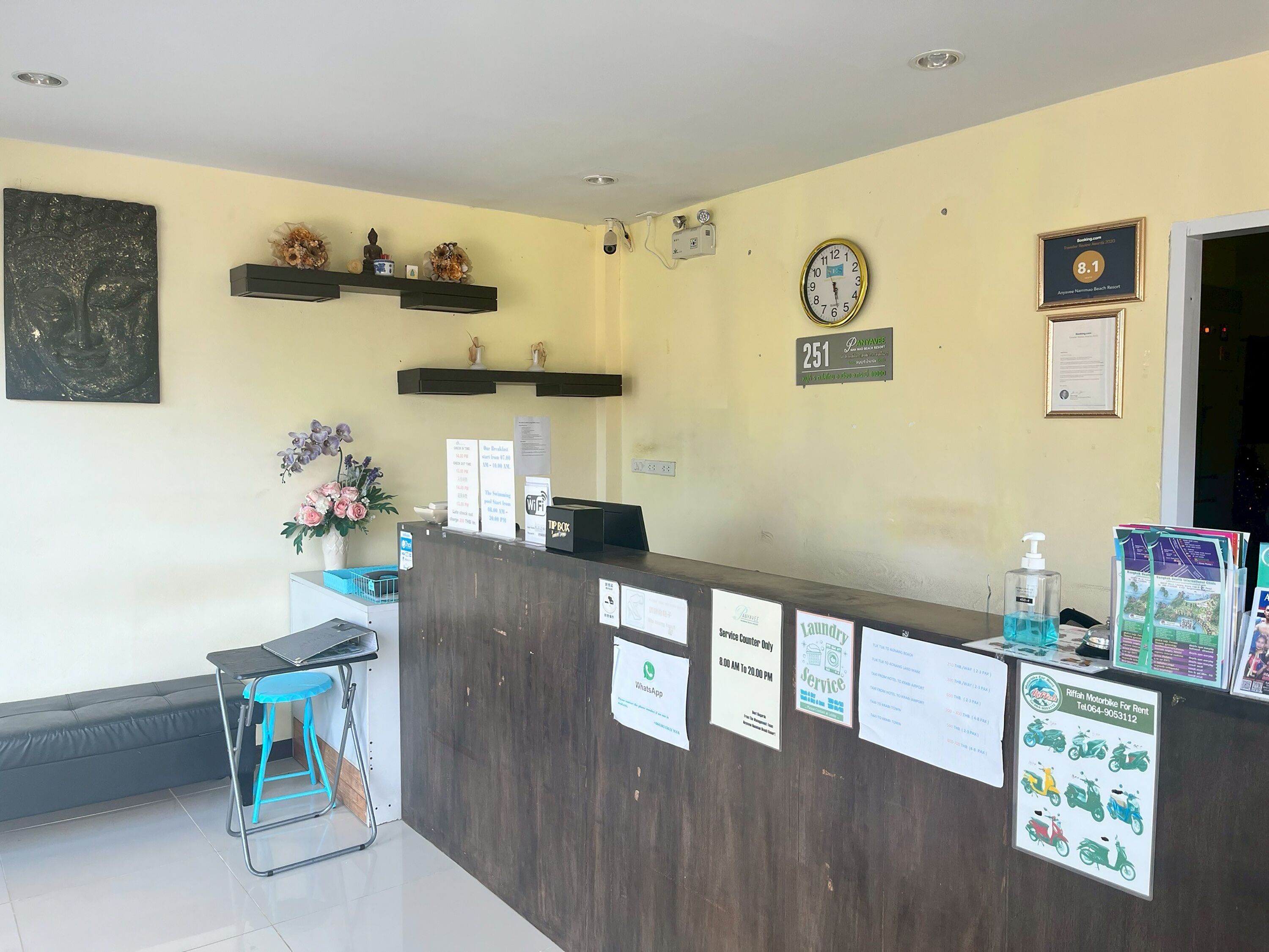 A reception desk with a clock, a framed certificate, and various informational signs.