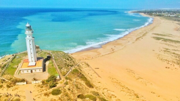 Un faro en una playa arenosa con una vista despejada del océano.
