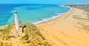 Un phare se dresse sur une plage de sable, offrant une vue dégagée sur l’océan.
