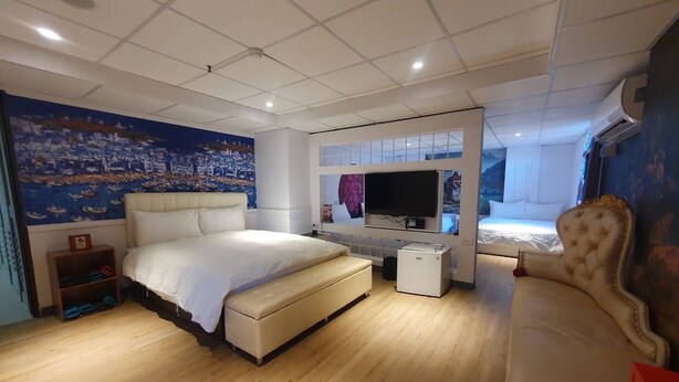 A modern bedroom with a large bed, a television, and a small refrigerator. - ARTHOME HOTEL (Kaohsiung)
