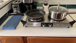 Eine Küche mit einem Herd, einer Pfanne, einem Topf, einem Toaster und einer Kaffeemaschine.
