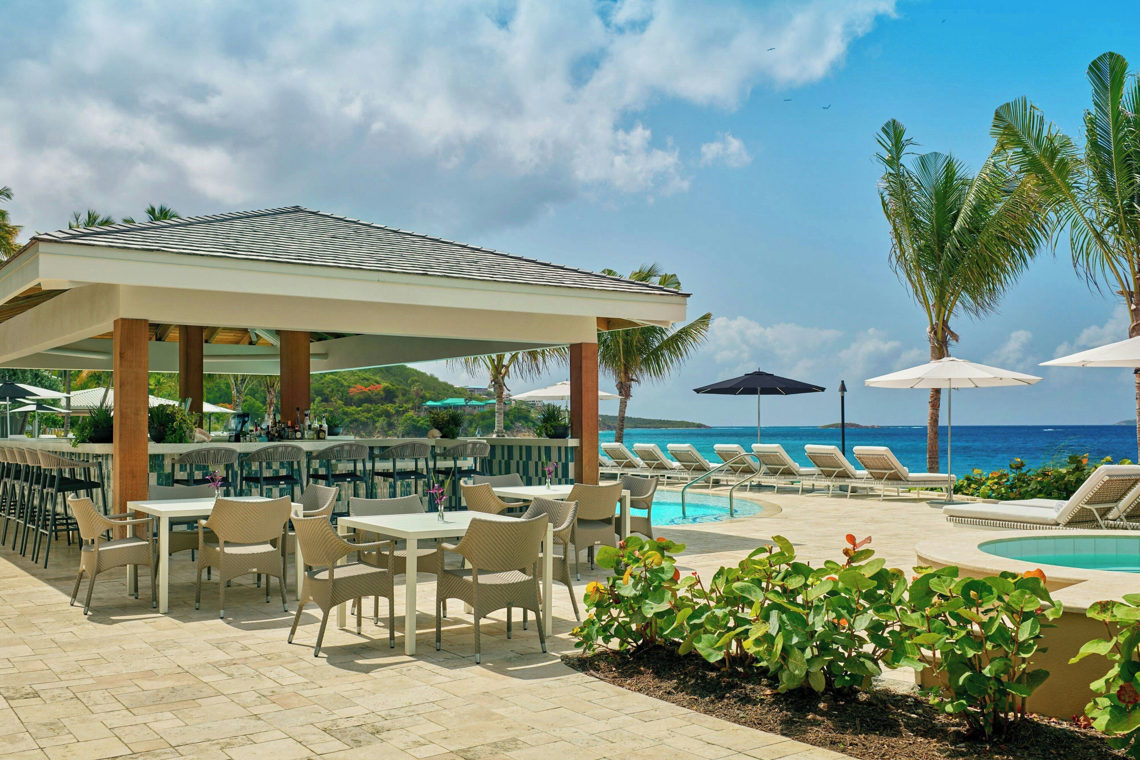 A poolside area with lounge chairs, a bar, and a covered seating area.