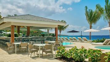 A poolside area with lounge chairs, a bar, and a covered seating area.