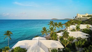 Un hotel costero con techos blancos, palmeras y vistas al océano.