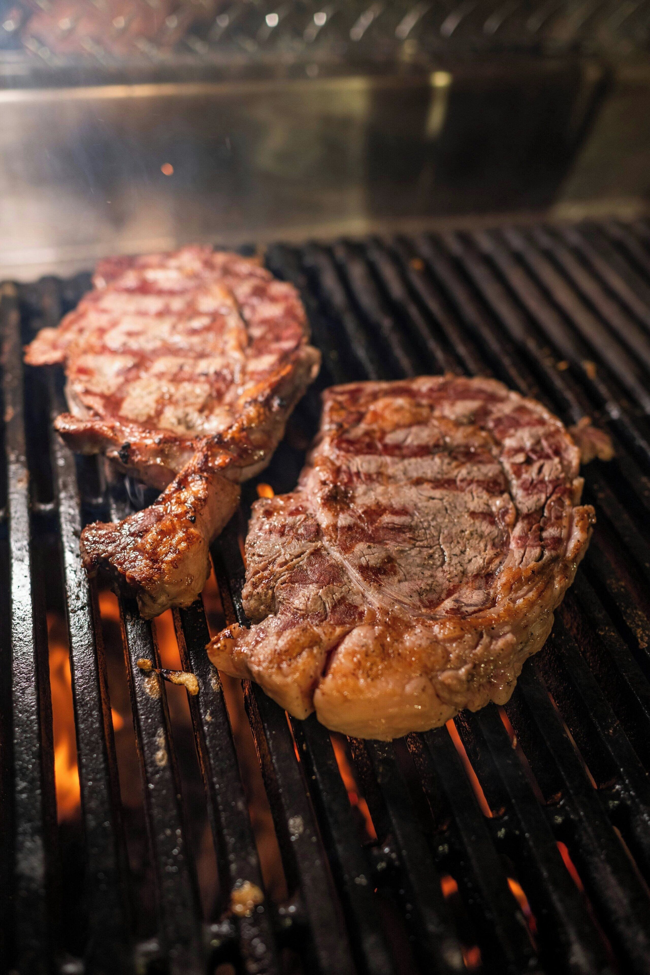 Steaks being grilled on a grill.