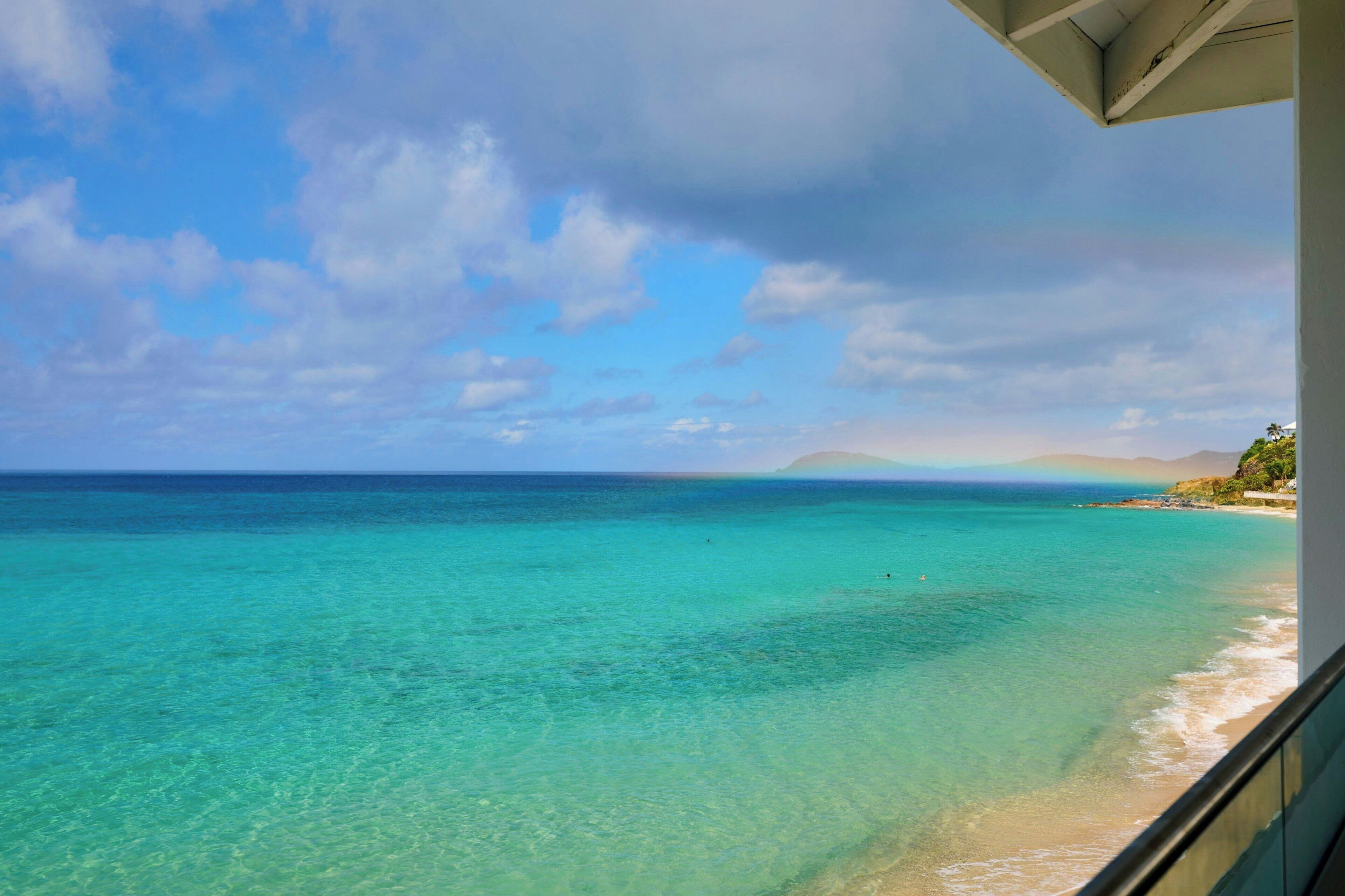 A clear view of a beach with turquoise water and a distant mountain range.