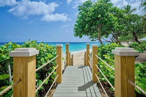 A wooden pathway leading to a beach with a clear view of the ocean and palm trees. - Buoy Haus Beach Resort St. Thomas, Autograph Collection (St. Thomas)