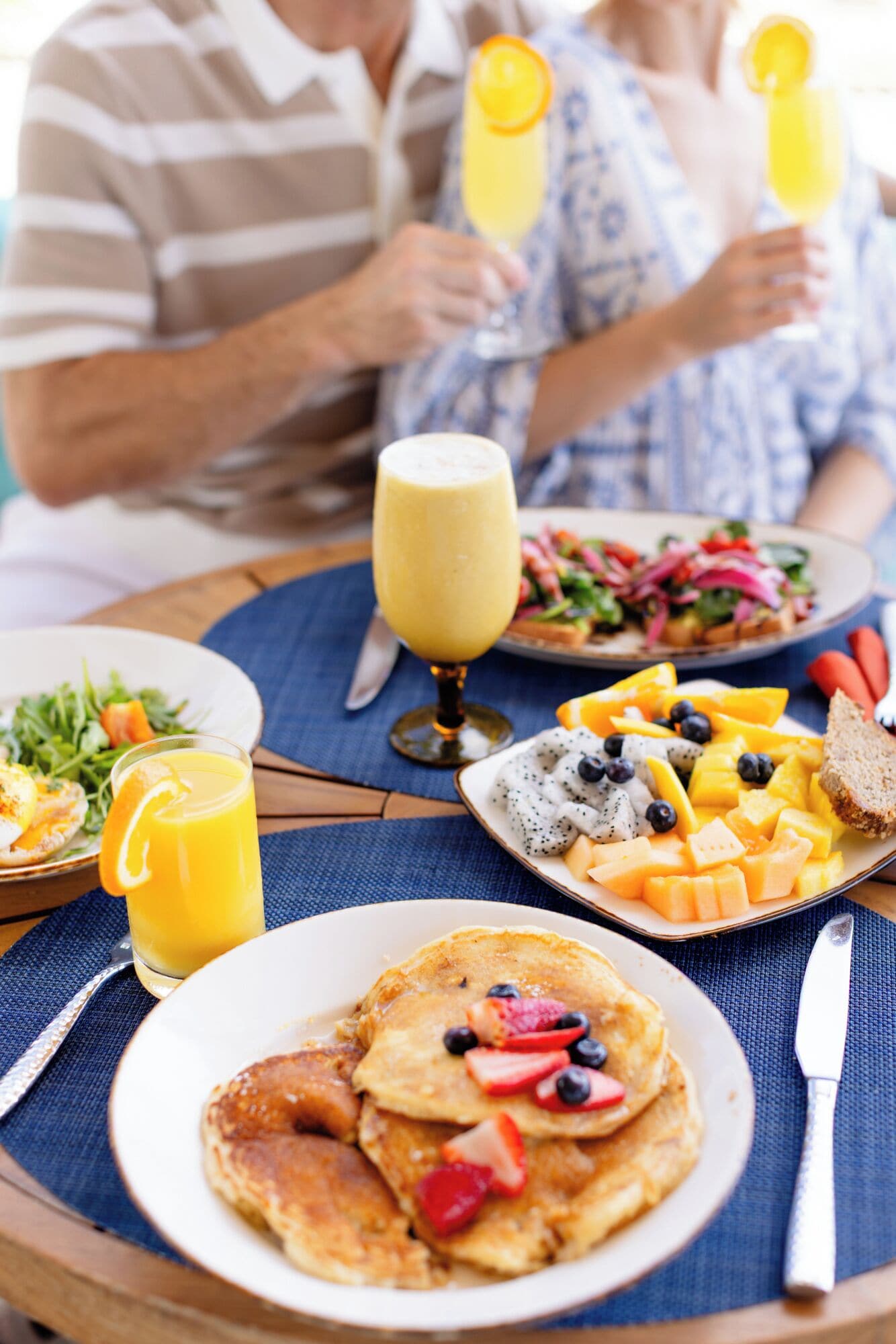 A breakfast setting with pancakes, fruit, and juice.