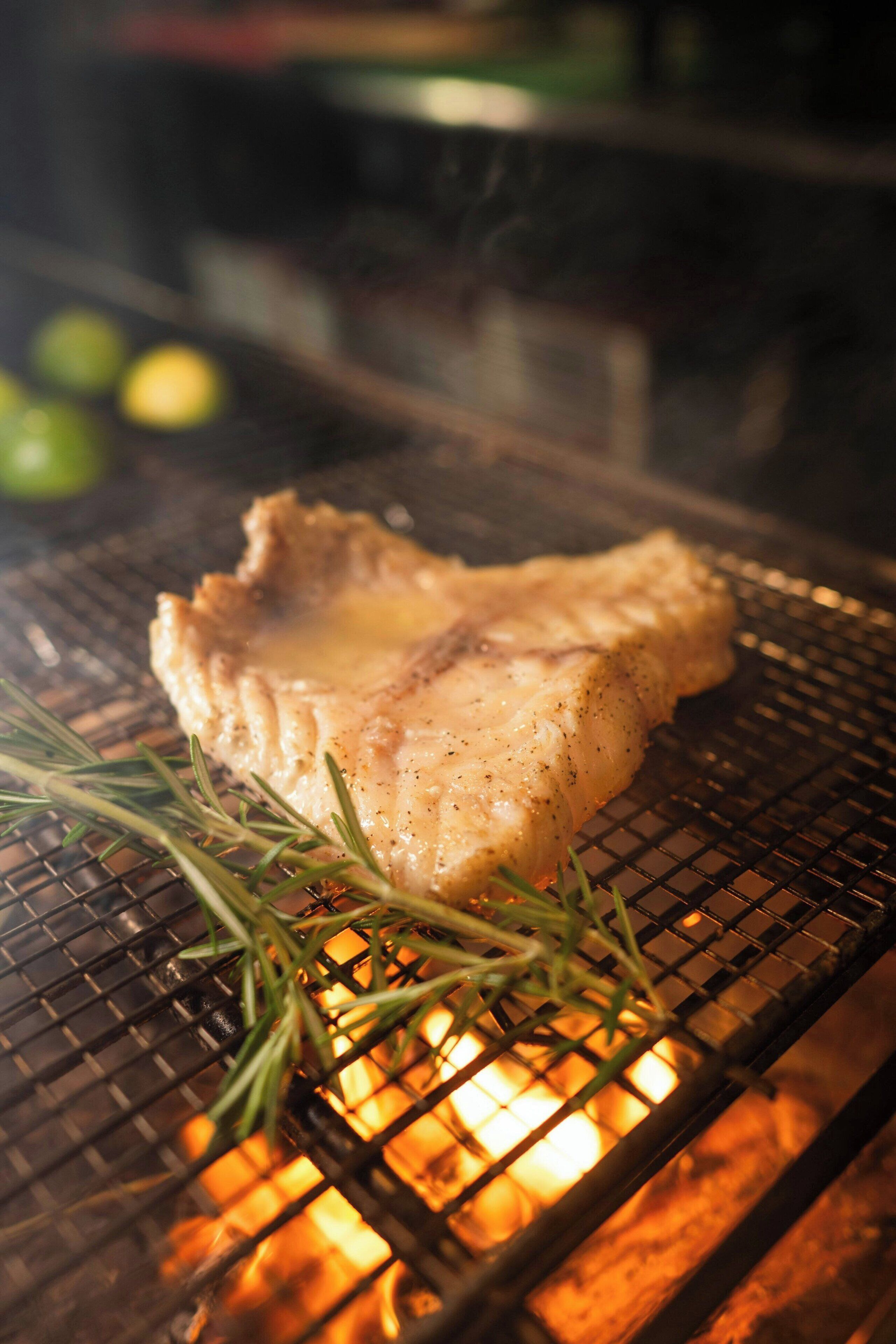 Een gegrilde steak met rozemarijn op een barbecue.