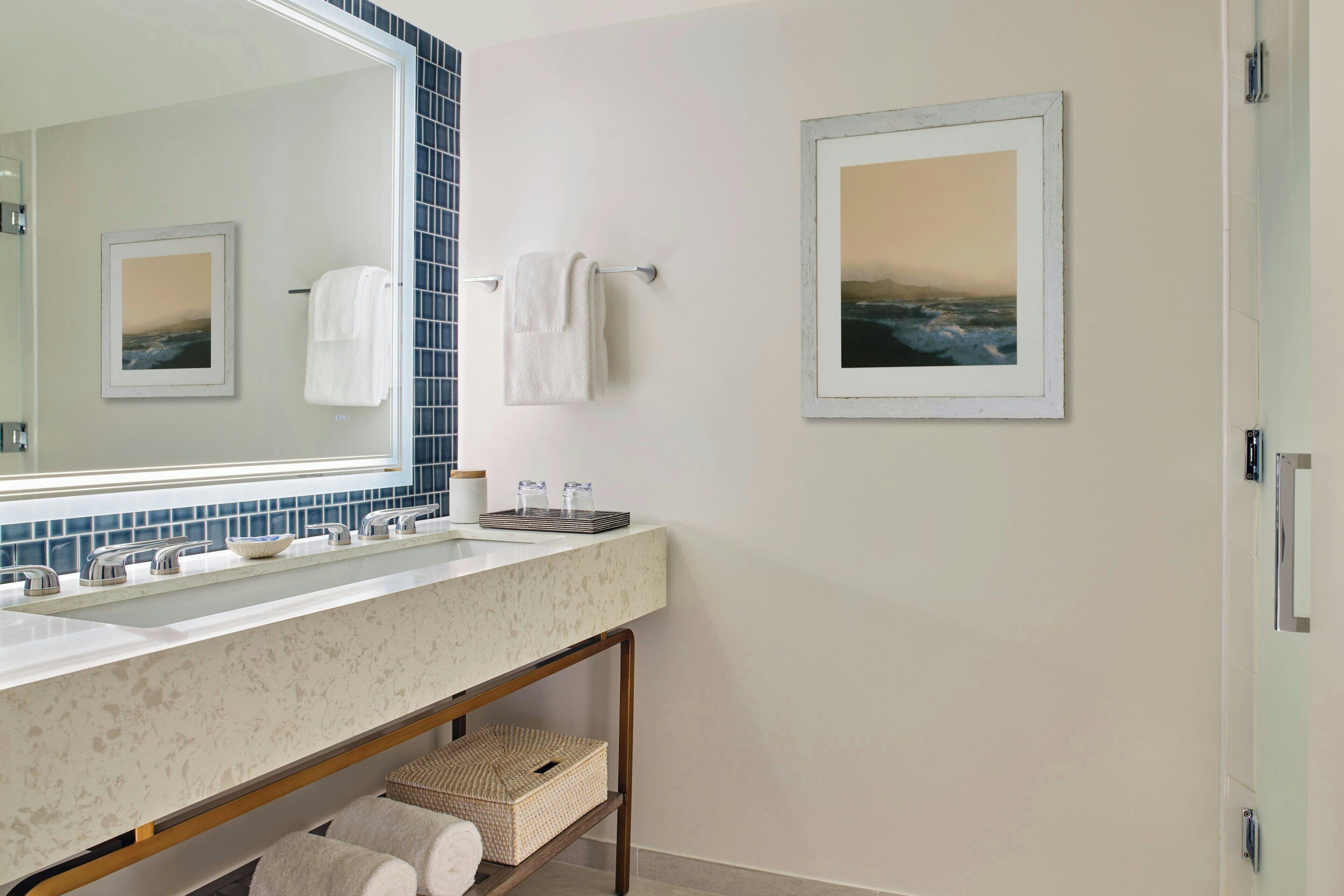A modern bathroom with a large mirror, two sinks, and a towel rack.