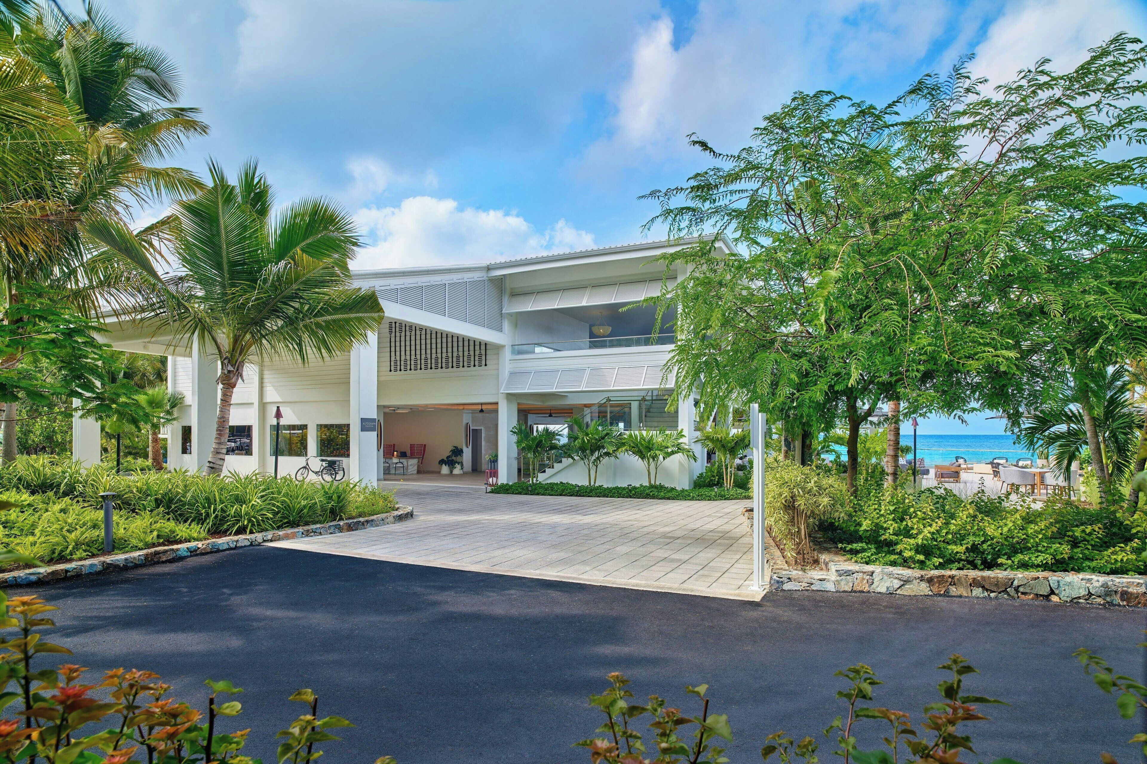 A modern hotel with a spacious entrance, a covered outdoor area, and a view of the beach.