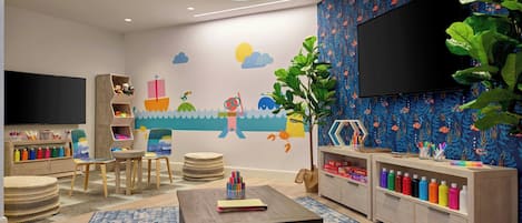 Une salle de jeux pour enfants décorée sur le thème de la marine, avec une fresque murale, des meubles en bois et un téléviseur.