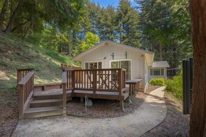 A small cabin with a wooden deck and a covered porch, surrounded by dense forest. - Redwood Retreat - Great for Families (Scotts Valley)