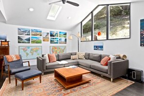 Ein modernes Wohnzimmer mit einem Ecksofa, einem Couchtisch, einem gemusterten Teppich und einer Weltkarte als Wandbild.