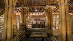 Un intérieur à thème bambou, avec un espace salon central et une cuisine visible à travers une cloison ajourée.