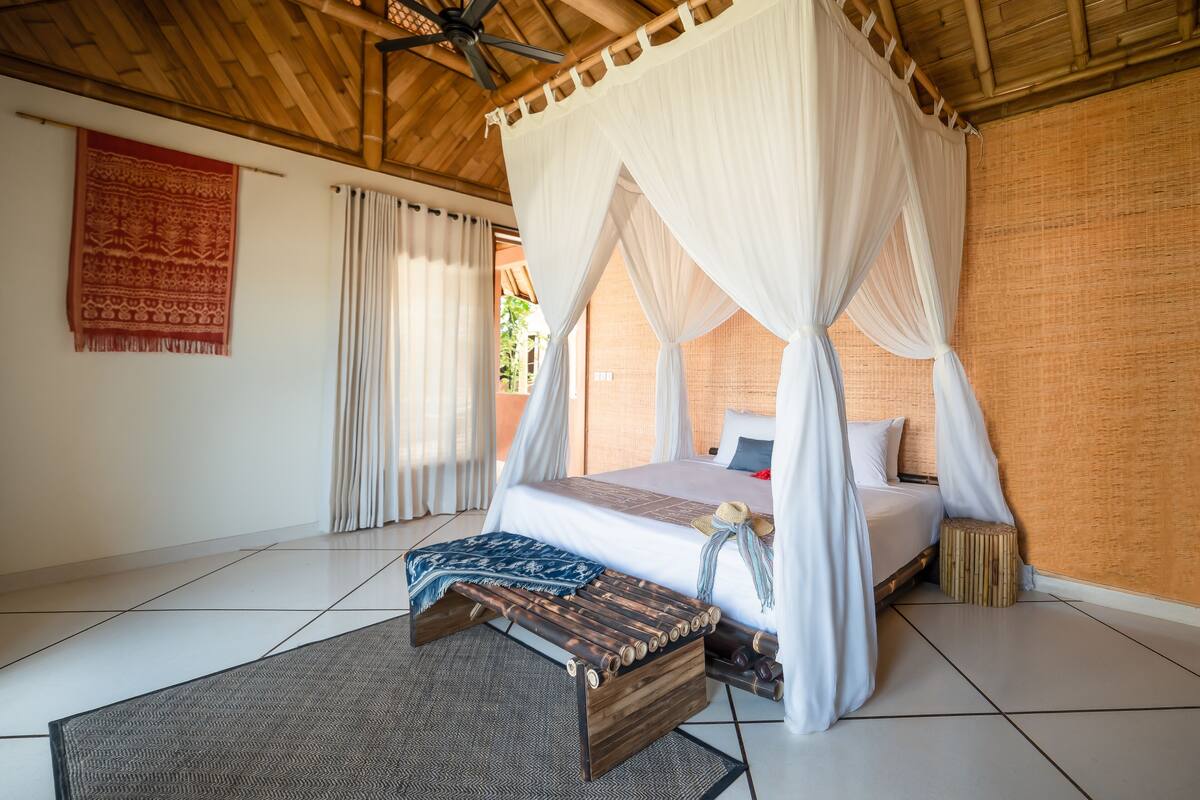 A room with a bed under a canopy, a wooden ceiling, and a patterned rug.