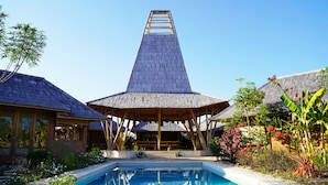 Un complexe hôtelier doté d’une piscine, de structures en bois et de plantes tropicales.