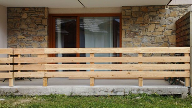 A wooden bench in front of a stone wall with a glass door. - Studio Résidence LE Parc DES Airelles (LES ORRES 1800)