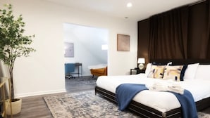A modern bedroom with a large bed, a dark headboard, and a patterned rug. - 5BR Game Room Near Cleveland Clinic (Cleveland Heights)