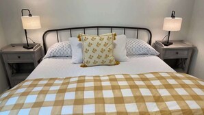 A bed with a checkered bedspread, two bedside lamps, and a nightstand with a drawer. - Chic Retreat: Your Cozy Getaway with Waffles too! (Orem)