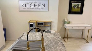 A kitchen with a marble countertop, gold faucet, and a framed sign on the wall. - Chic Retreat: Your Cozy Getaway with Waffles too! (Orem)