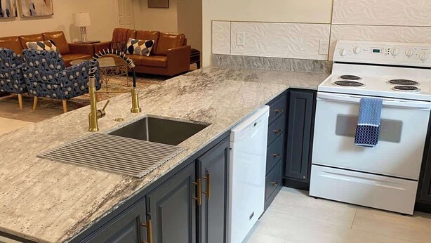 A kitchen with a granite countertop, a sink, a stove, and a dishwasher. - Chic Retreat: Your Cozy Getaway with Waffles too! (Orem)