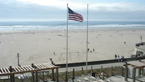 Une plage avec un drapeau américain, une aire de jeux et une promenade en bord de mer dotée de bancs.