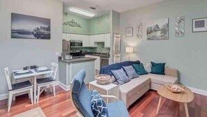 A compact living space with a kitchenette, a dining area, and a seating area with a sofa and a chair. - 6x Gamer Themed 2BR Apts - Close to Stadium! (Jacksonville)