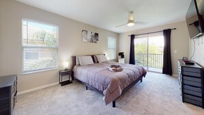 A bedroom with a bed, nightstands, a dresser, a ceiling fan, and a balcony with a view. - PERFECT, NEW! 6 Min to Dis, On Lake, Brand Name Beds, Big  T.Vs, Steps to Pool.  (Kissimmee)