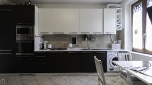 A compact kitchen with a built-in oven, a coffee maker, and a washing machine. - Italianway - Andrea Ponti 1 (Milan)