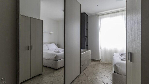 A modern bedroom with a bed, wardrobe, and a built-in shelf unit. - Italianway - Andrea Ponti 1 (Milan)