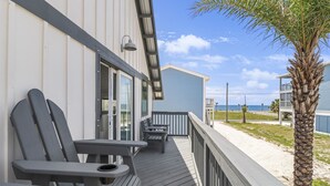 A wooden deck with two Adirondack chairs and a table, overlooking a sandy beach and the ocean. - Sugar Sand Cottage A (Port St. Joe)