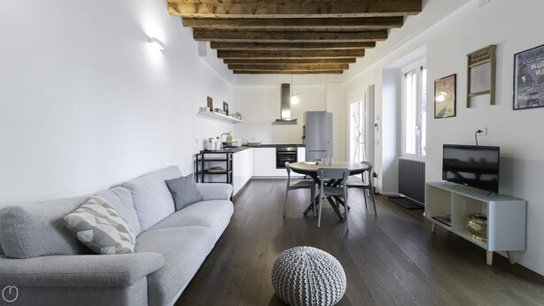 A modern living room with a grey sofa, a round coffee table, and a TV on a stand. - Italianway Comfort - Alfieri 18 (Milan)