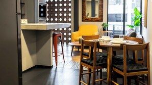 Una cocina moderna con comedor, que cuenta con un amplio ventanal, una silla amarilla y un espejo en la pared.
