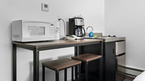 Et kompakt tekøkken med mikrobølgeovn, kaffemaskine og et lille køleskab.