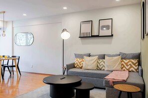 A modern living room with a grey sofa, two black side tables, a round coffee table, and a floor lamp.