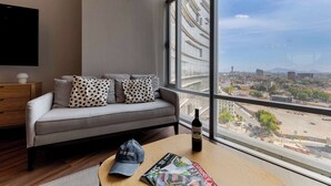 A modern living room with a grey sofa, a wooden coffee table, and a large window offering a city view. - Capitalia | Refined Duplex | Full Gym & Security (Ciudad de México)