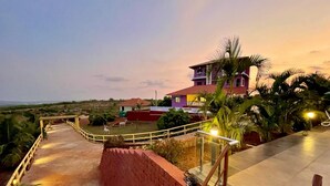 Un hotel con una escalera de ladrillo rojo que lleva a una terraza con vistas al paisaje circundante y un edificio grande con techo rojo.