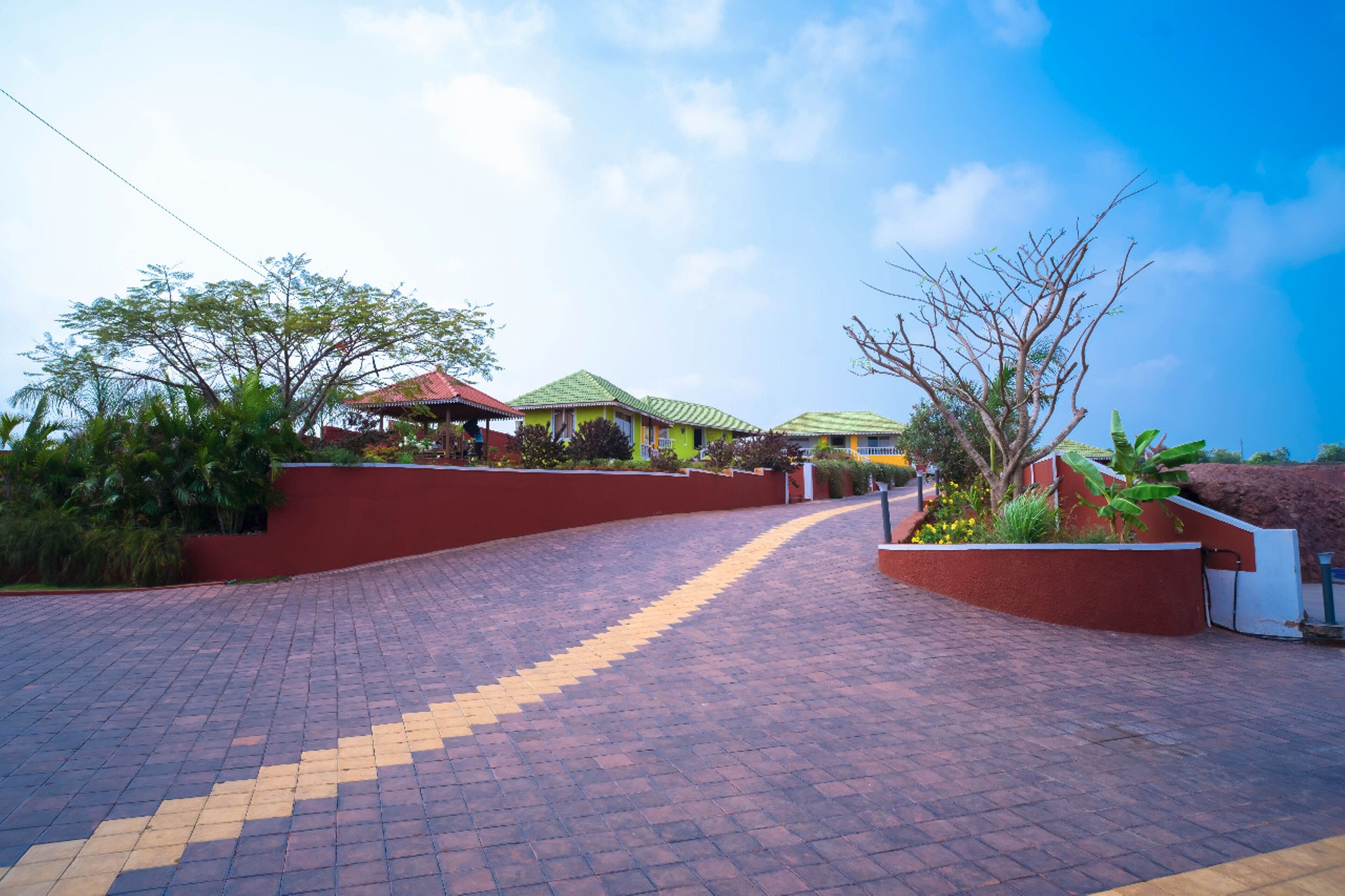 A paved pathway leading to a building with a red wall and green roof.
