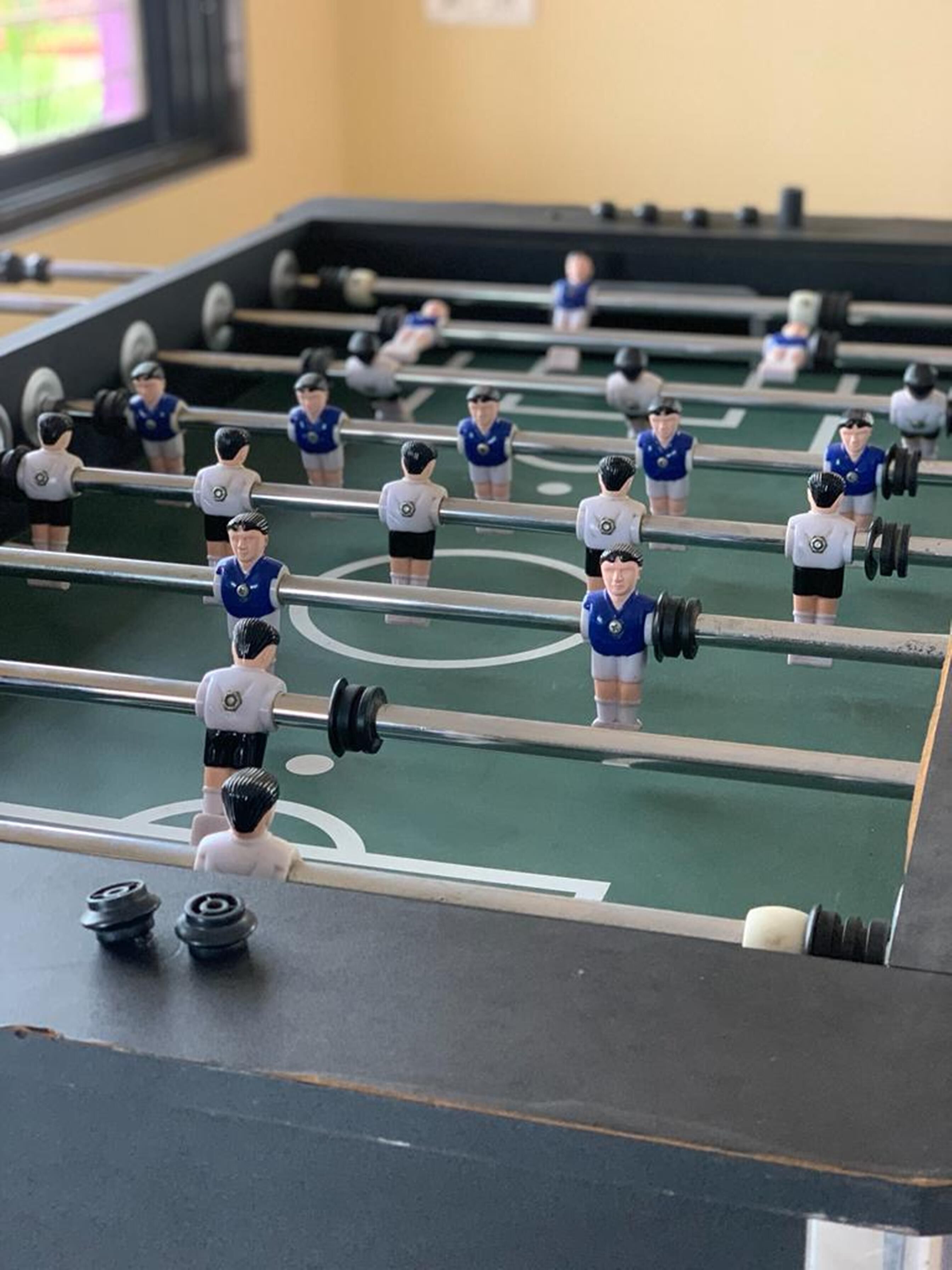 A foosball table with miniature figures in blue and white uniforms.