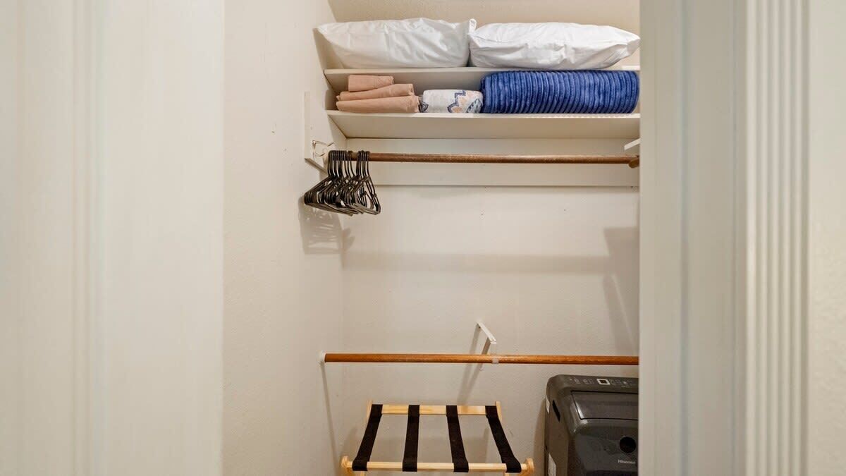 Ein kleiner Kleiderschrank mit Regalen für gefaltete Kleidung und einer Kleiderstange.