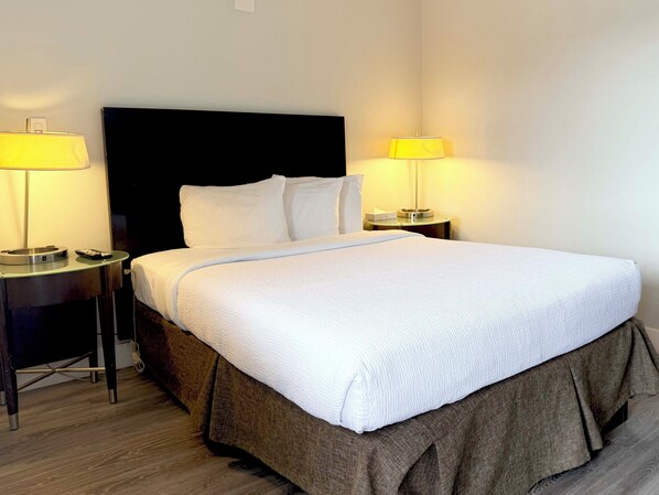 A hotel room with a bed, two bedside tables, and two lamps. - Departure Bay Motel (Nanaimo)