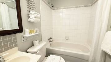 A bathroom with a sink, toilet, and bathtub. There are towels and toiletries on the wall.
